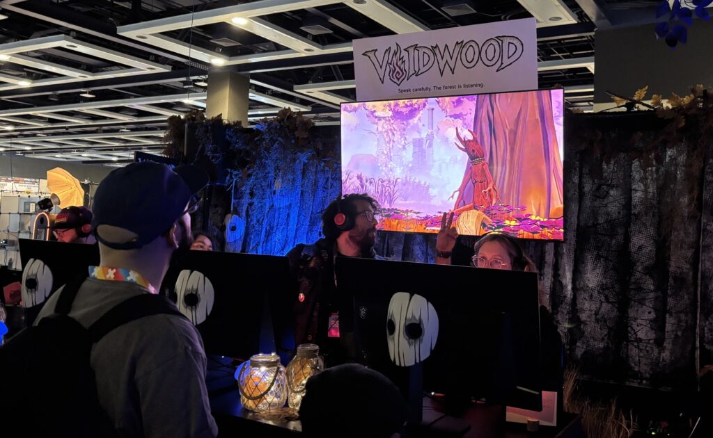PAX West 2026: People look on at a screen, with the Voidwood logo above it.