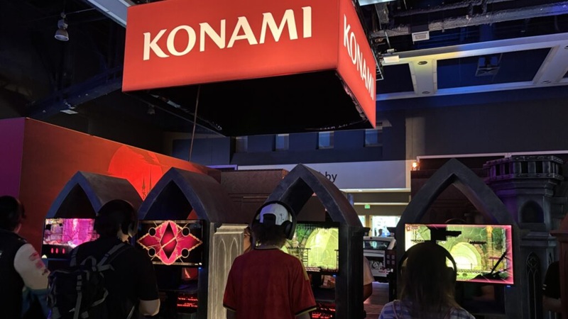 Pax West 2026: Gamers play on arcades as they stand below the Konami logo.