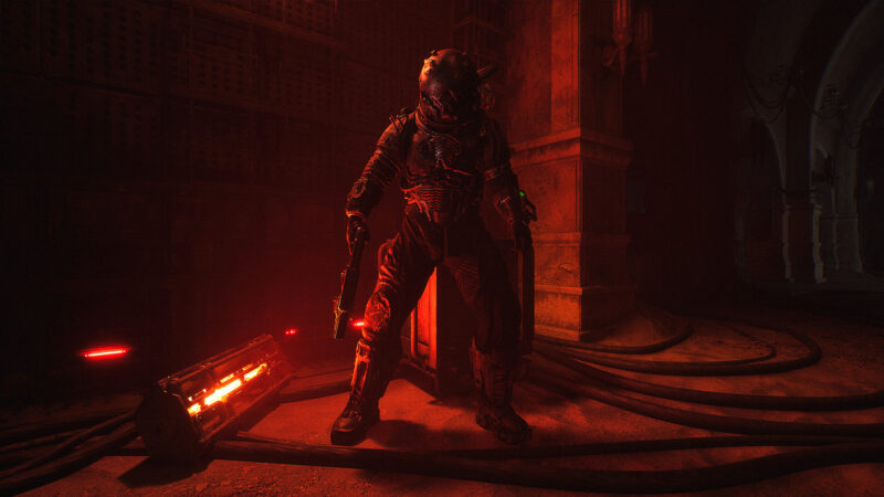 Cronos: Lazarus: someone in a futuristic-looking spacesuit stands tall in a dark room bathed in an ominous red light.