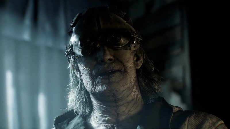 Resident Evil Requiem: a ghoulish-looking man with long hair and cracked skin wears some menacing goggles.
